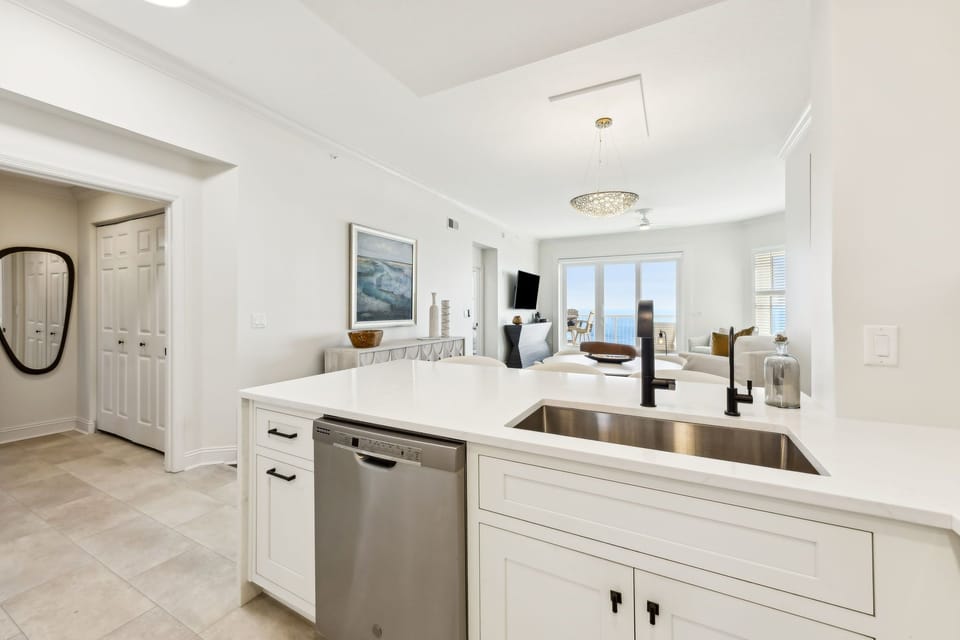 Luxury Modern Kitchen Featuring Waterfall Quartz Countertops, Stainless Steel Appliances, and Barstool Seating for 3