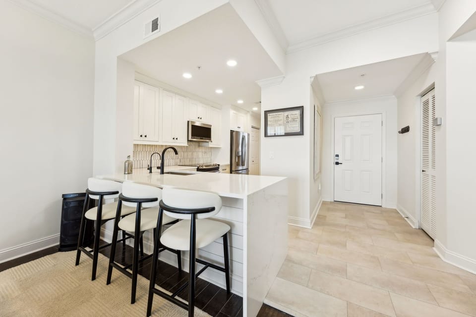 Luxury Modern Kitchen Featuring Waterfall Quartz Countertops, Stainless Steel Appliances, and Barstool Seating for 3