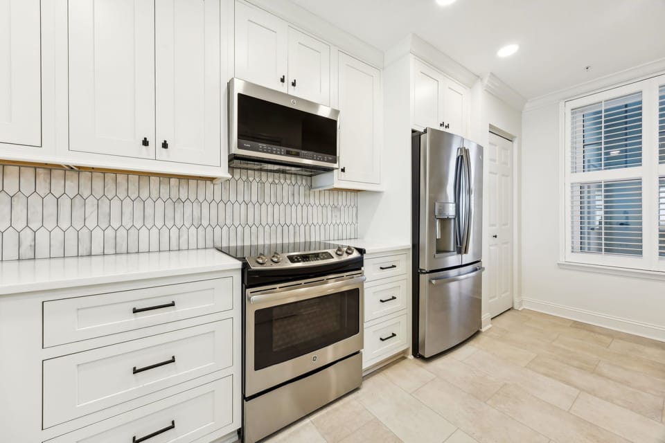 Luxury Modern Kitchen Featuring Waterfall Quartz Countertops, Stainless Steel Appliances, and Barstool Seating for 3