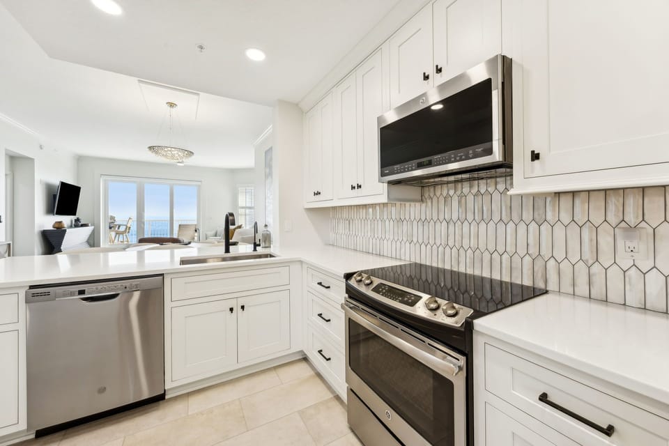 Luxury Modern Kitchen Featuring Waterfall Quartz Countertops, Stainless Steel Appliances, and Barstool Seating for 3