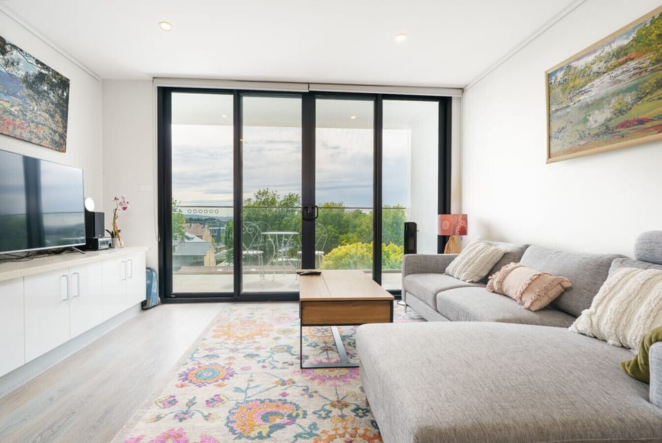 Bright, cozy living space with balcony access and leafy outdoor views.
