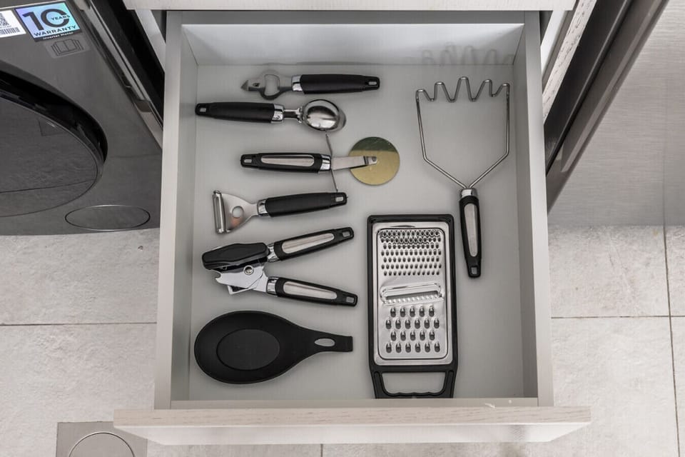 Organized drawer with cutlery, measuring spoons, and kitchen essentials.