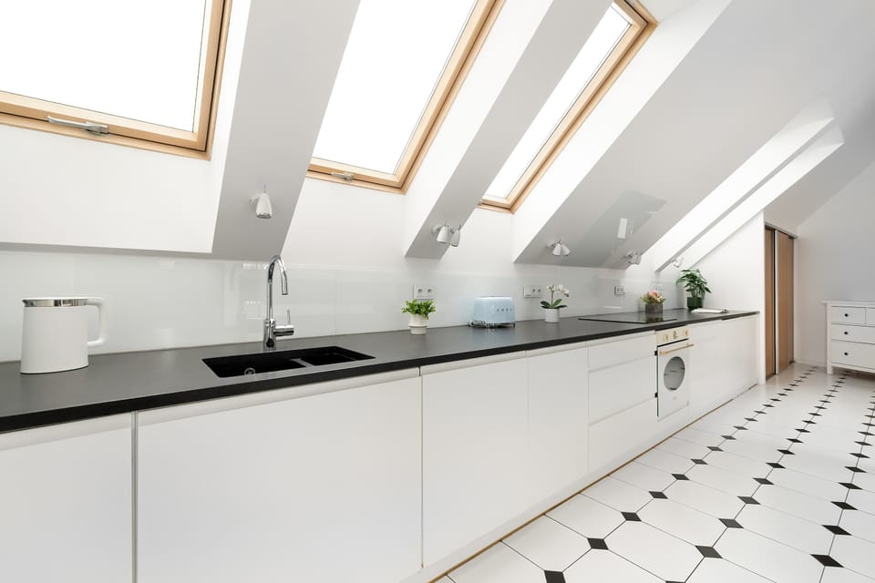 A bright kitchen with white cabinets and skylights. The minimalist style makes the space feel open and clean.