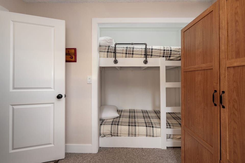 Cozy bunk beds with charming plaid linens create your perfect retreat. Built-in design maximizes space while maintaining comfort for restful nights.
