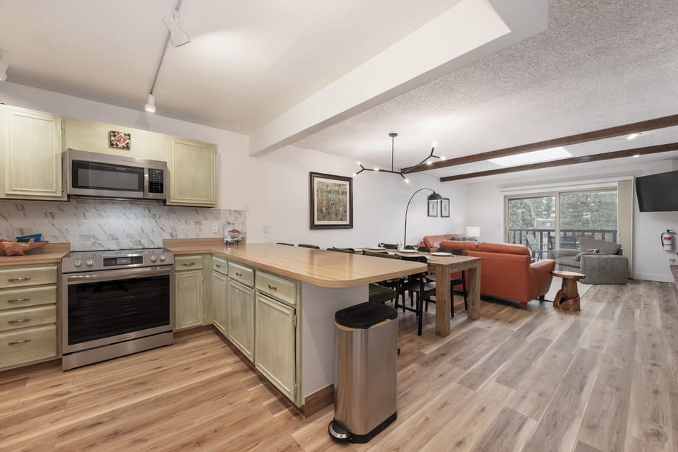Your open-concept kitchen flows seamlessly into the living area, perfect for cooking and entertaining with modern appliances and warm wood finishes.