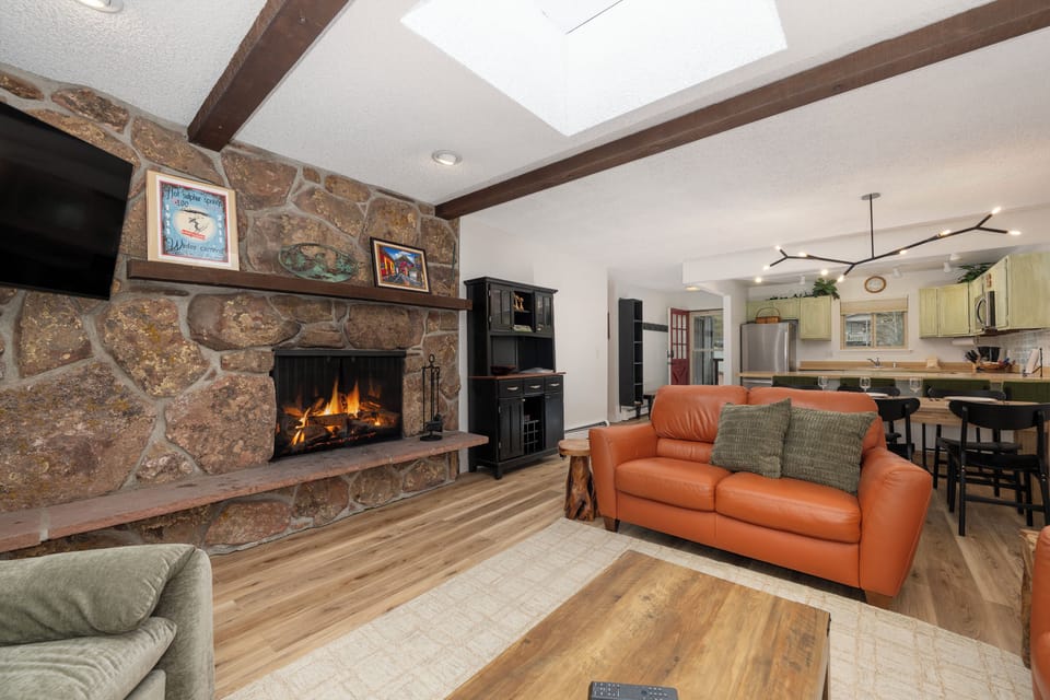 Unwind by your crackling stone fireplace while soaking up natural light from the skylight above in this inviting open-concept space.