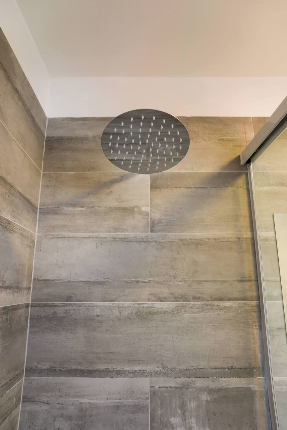 Experience a refreshing rain shower in a sleek, modern bathroom with stylish gray tiles.