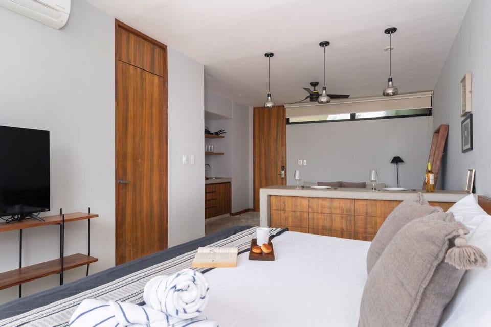 Bright modern studio with a soft king bed and warm wooden accents.