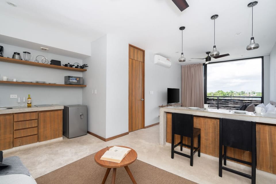 Bright studio with cozy living area, dining island, and tropical views.