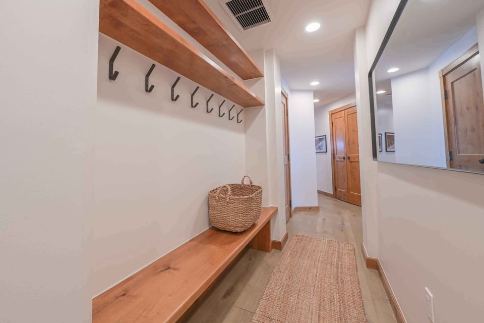 A charming entryway features rustic wooden shelves and hooks, perfect for storing outdoor gear after mountain adventures.