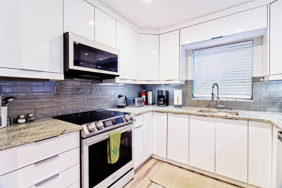 Fully equipped contemporary kitchen featuring clean white cabinetry, granite counters, and top appliances. Ideal for families and long stays