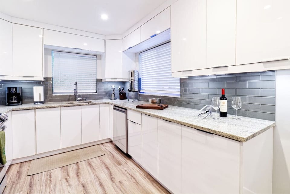 Fully equipped contemporary kitchen featuring clean white cabinetry, granite counters, and top appliances. Ideal for families and long stays