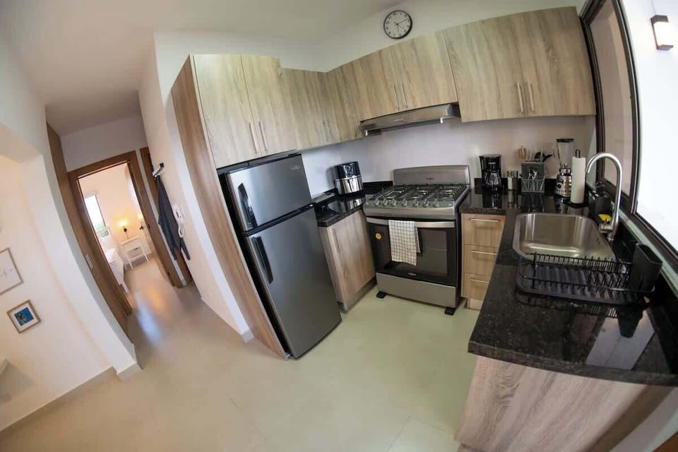 - Modern kitchen with fridge stove oven and full cabinetry
- Designed for cooking daily meals and longer stays
- Clean functional space with storage appliances and light
