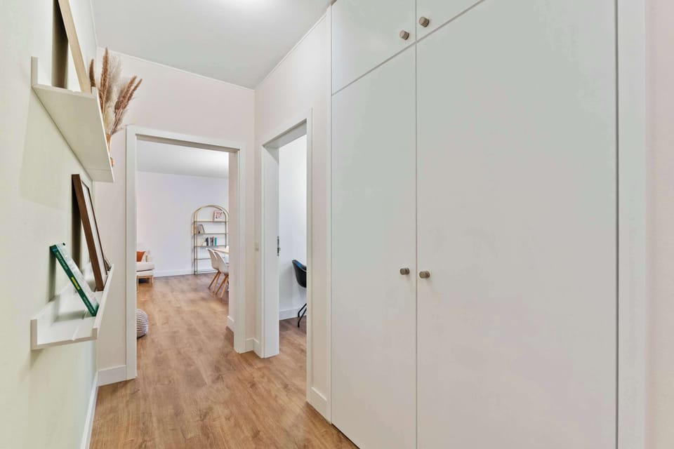Spacious hallway with large built-in closets providing ample storage. A bright and organized space that connects the living room, bathroom, and bedroom seamlessly.