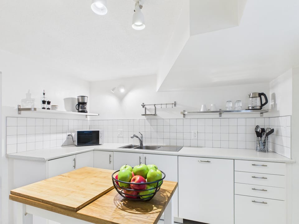 A chef-ready kitchen setup showing bright white cabinetry, prep space, and microwave.