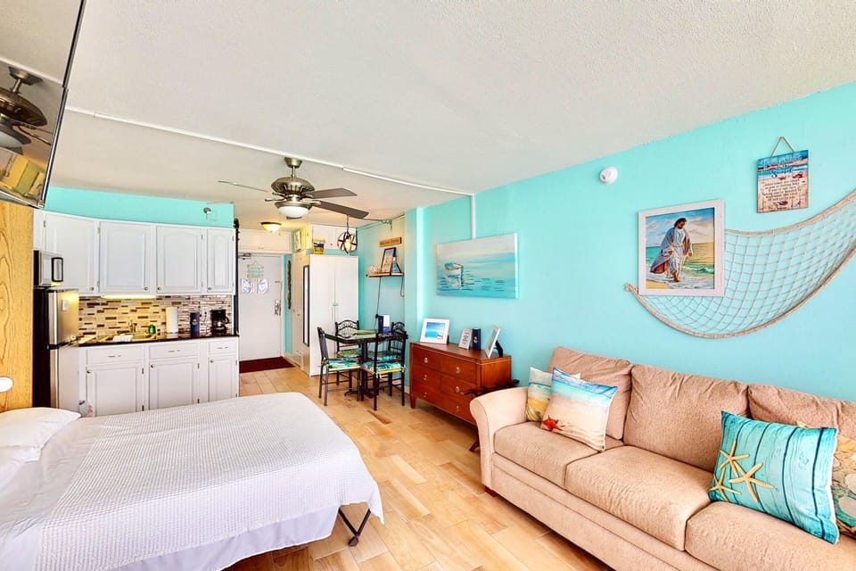 Cheerful beach-themed studio featuring soft aqua tones, coastal art, and comfy seating. A perfect, relaxing space for your beach stay after sun-filled days by the shore.