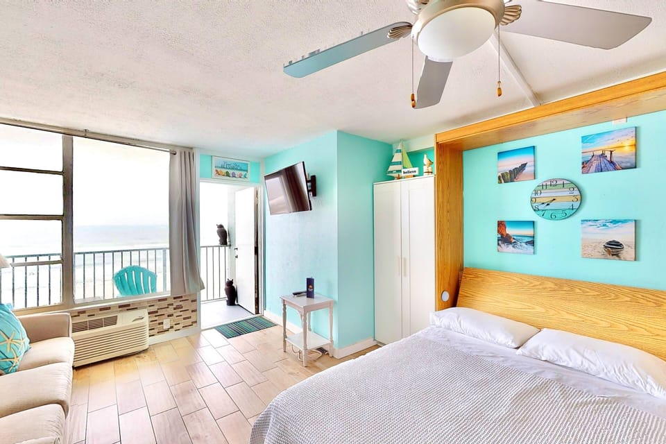 Colorful beach-themed studio with oceanfront views, comfy bedding, and vibrant décor. Enjoy a relaxing beach stay with bright turquoise accents, balcony access, and a cozy, coastal vibe throughout.