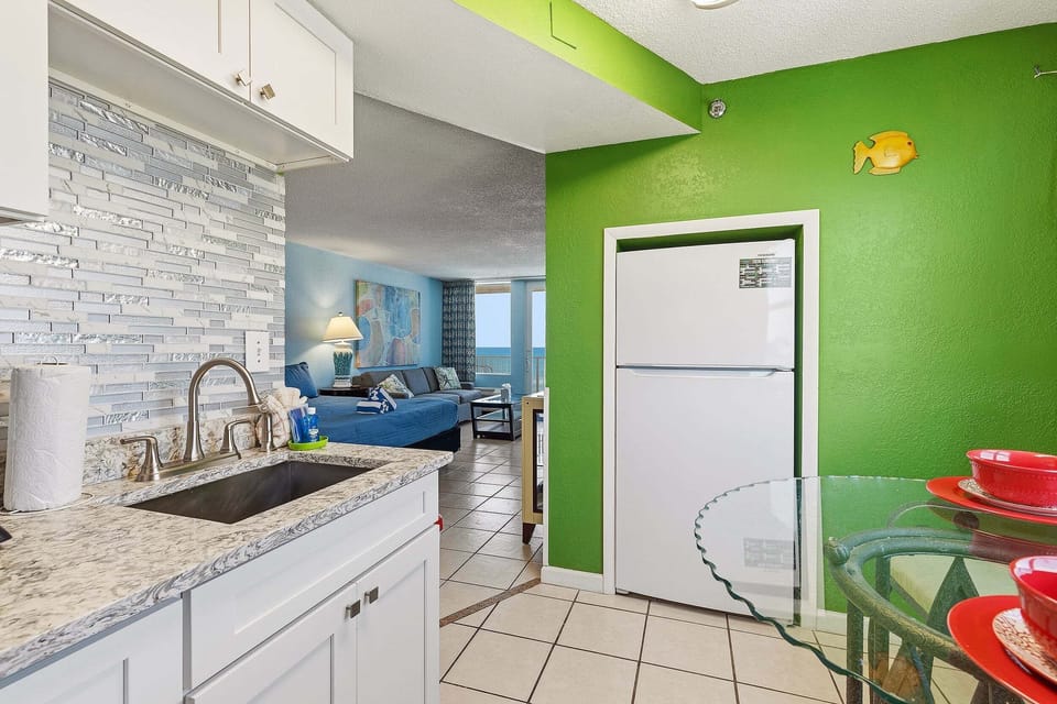 Cook with ease in this updated kitchen featuring granite countertops, modern cabinetry, full-size appliances, and a cozy dining area. The open layout flows into the living space, making it ideal for a relaxing beach stay.