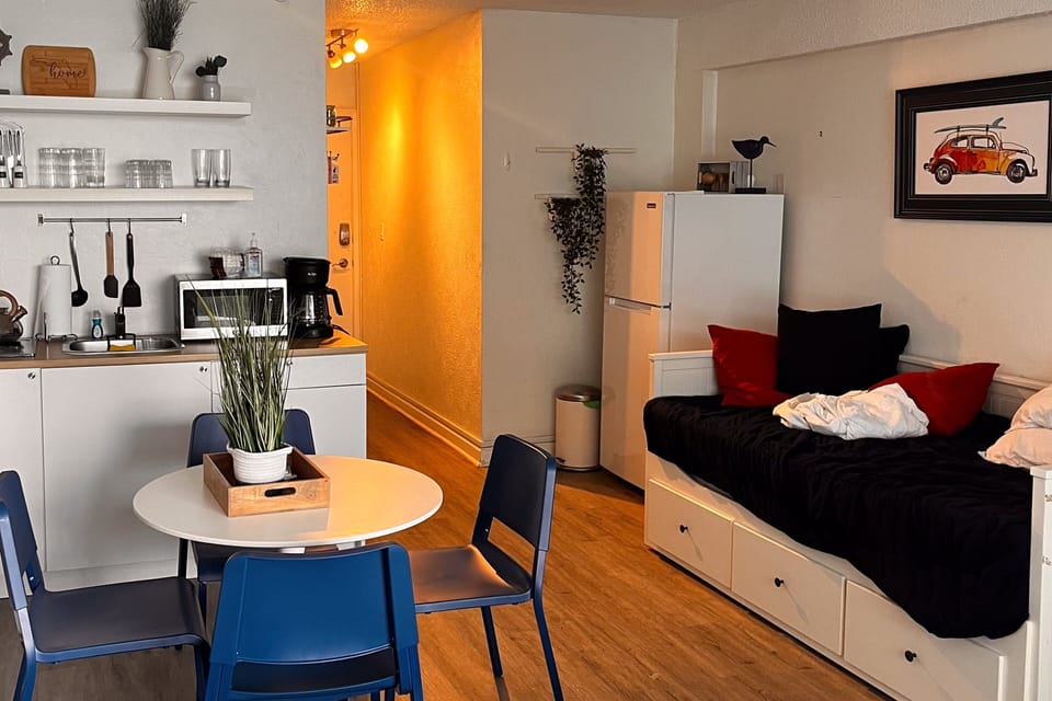 Inviting beach stay setup with a compact kitchen, dining table, and comfy daybed—perfect for relaxing after sun-filled adventures by the ocean.