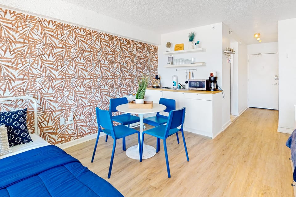 Colorful beach stay dining area with a stylish accent wall, fully equipped kitchenette, and cozy seating—perfect for meals and relaxing after sunny adventures.