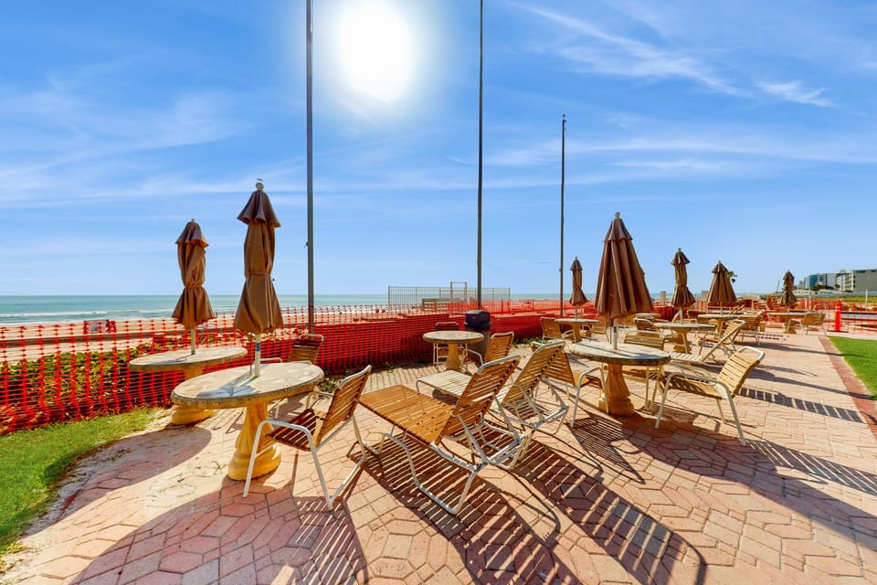 Soak up the sun in this oceanfront lounge area with tables, chairs, and umbrellas just steps from the sand. A perfect spot to unwind during your beach stay and enjoy ocean views, sea breezes, and coastal vibes.
