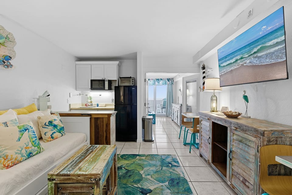 Enjoy this open-concept beach stay featuring coastal décor, a cozy living area, and a convenient kitchenette. Flowing into a dining space and private balcony, it's perfect for relaxing after a day at the beach and ocean adventures.