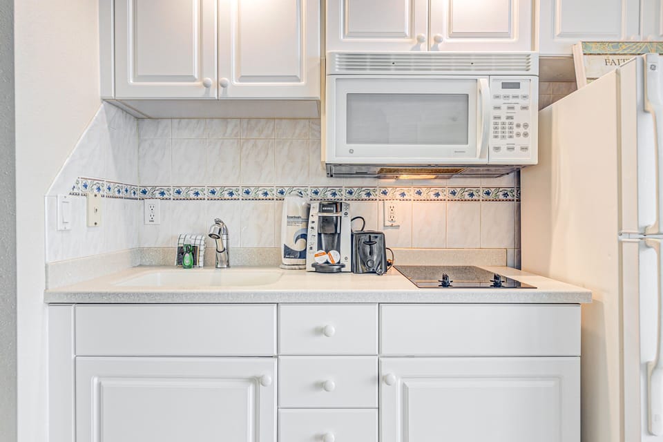 Cozy beach stay kitchenette with cooktop, microwave, and coffee maker. Perfect for preparing quick meals between ocean adventures. Clean, bright, and equipped for a comfortable coastal getaway.