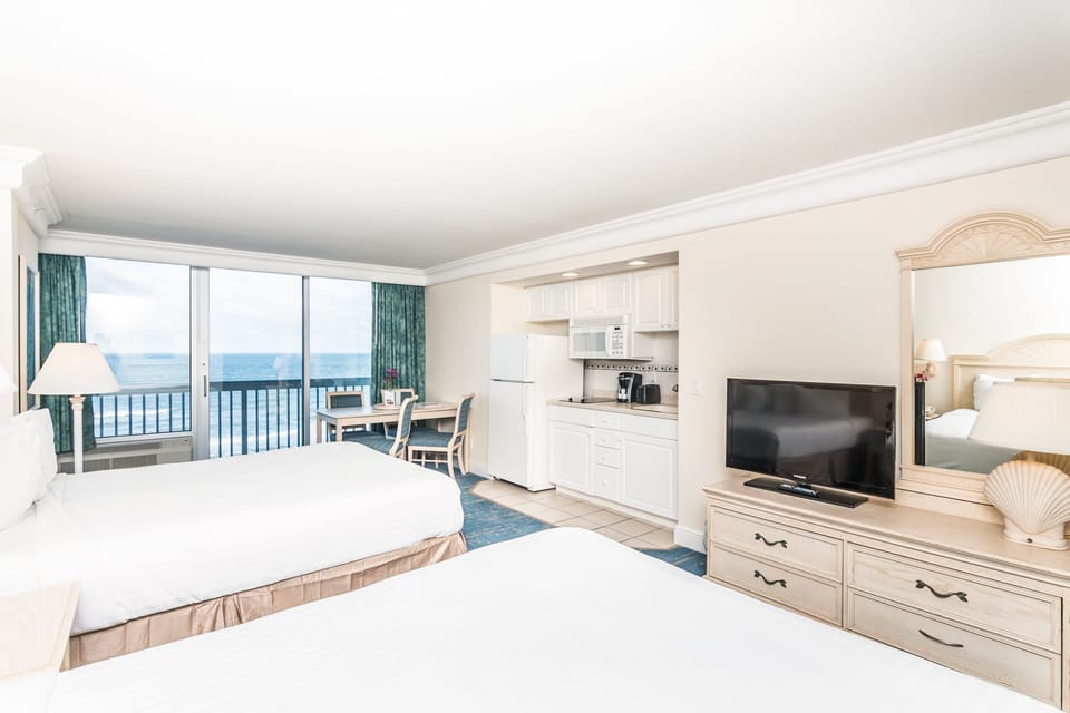 Bright oceanfront studio featuring two comfy beds, a full kitchenette, dining space, and sweeping beach views—perfect for a relaxing beach stay with all the comforts of home.