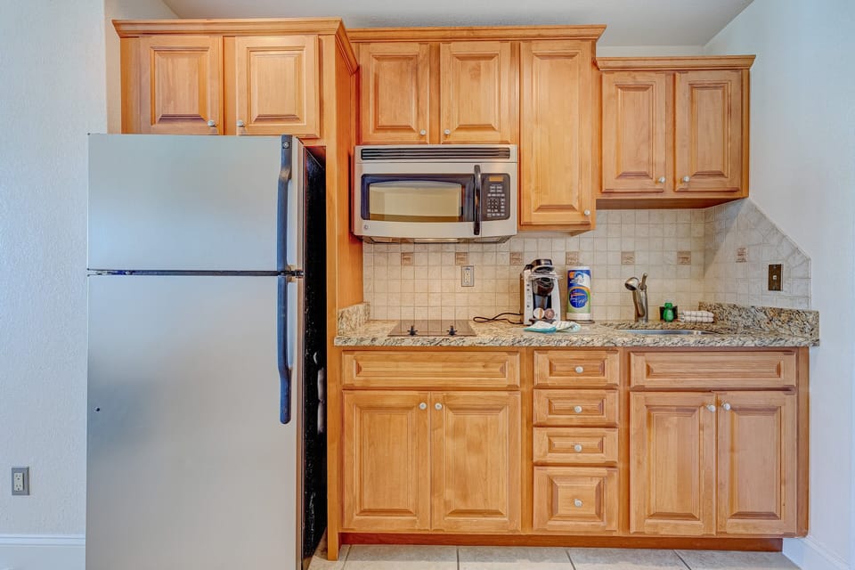Enjoy the convenience of a full kitchenette with granite counters, stainless fridge, microwave, and coffee maker—perfect for prepping meals and snacks during your relaxing beach stay.