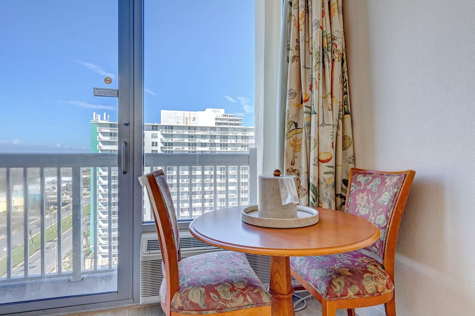 Enjoy a relaxing beach stay at this charming dining nook featuring vibrant seating and floor-to-ceiling window views of the coastline—perfect for morning coffee or sunset snacks.