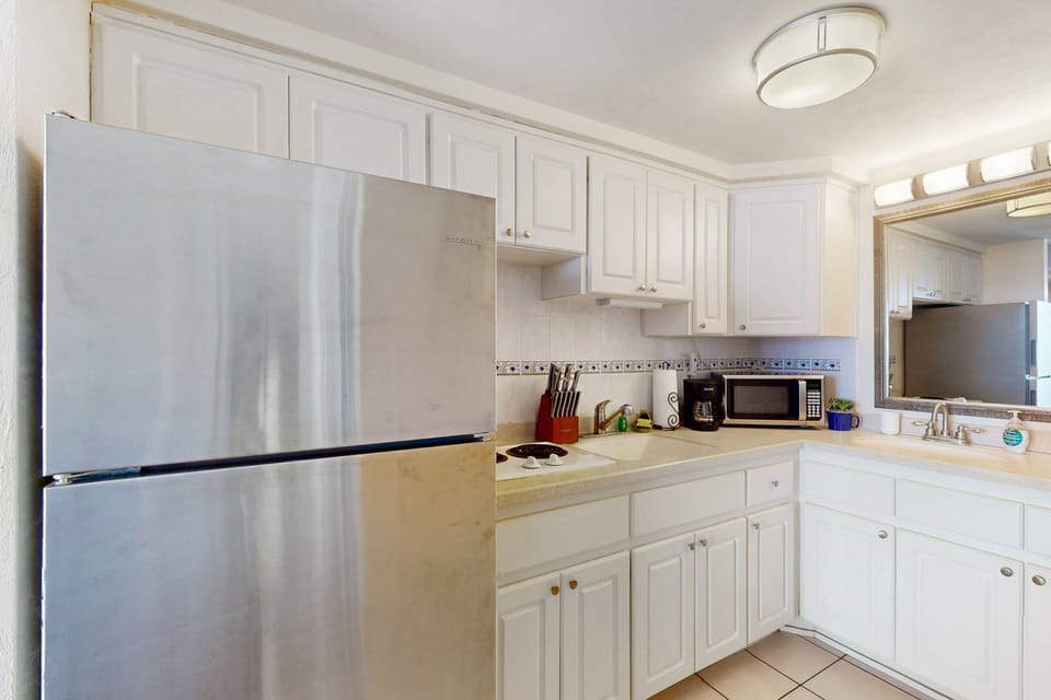 Bright, functional kitchen with full-size fridge, cooktop, microwave, and essentials—perfect for easy meals during your beach stay. A convenient space to refuel between oceanfront adventures.