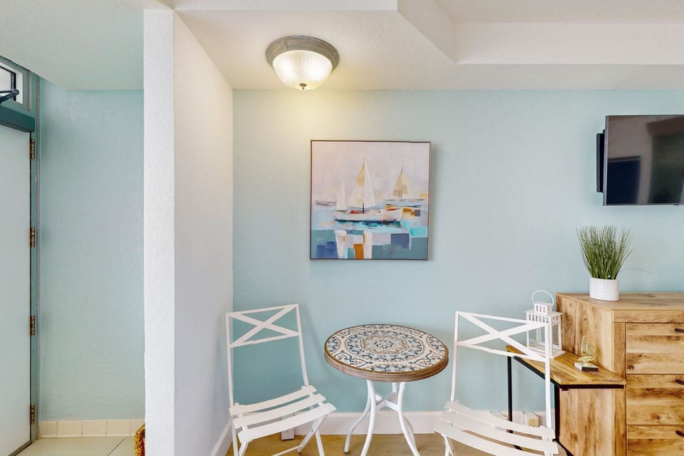 Charming bistro table set beside coastal décor creates a relaxing spot for morning coffee during your beach stay. Light, airy design complements ocean-view living steps from the shore.