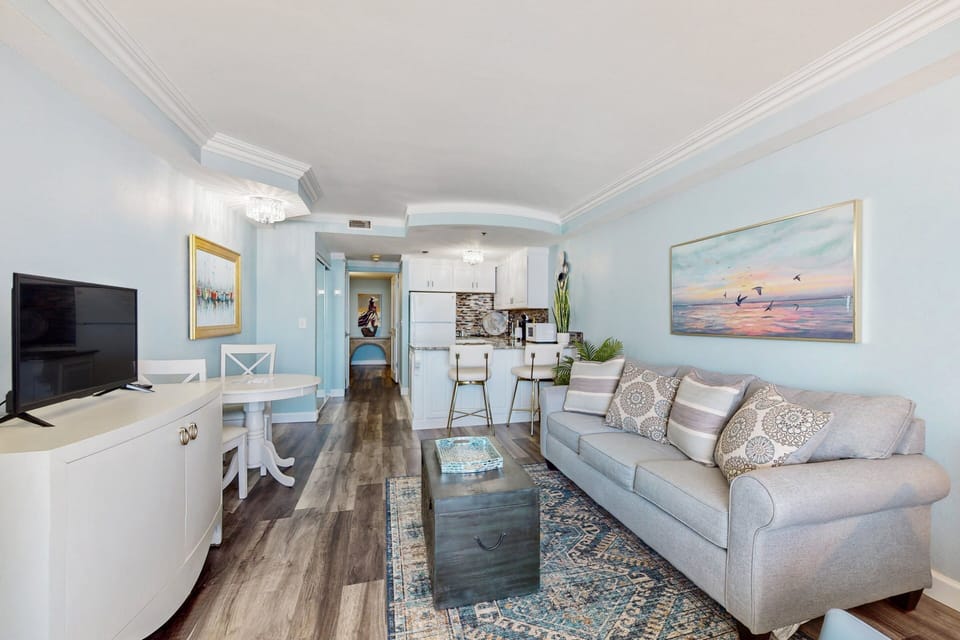 Relax in this open beach-stay living space featuring a comfy sofa, stylish décor, dining nook, and updated kitchen—perfect for unwinding after sun-filled days by the shore.