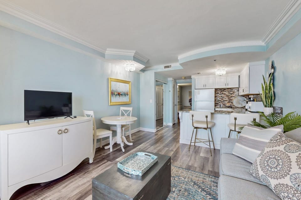 Enjoy this bright, beach-stay living space featuring a cozy seating area, dining nook, and stylish kitchen—perfect for relaxing and gathering after a day by the shore.