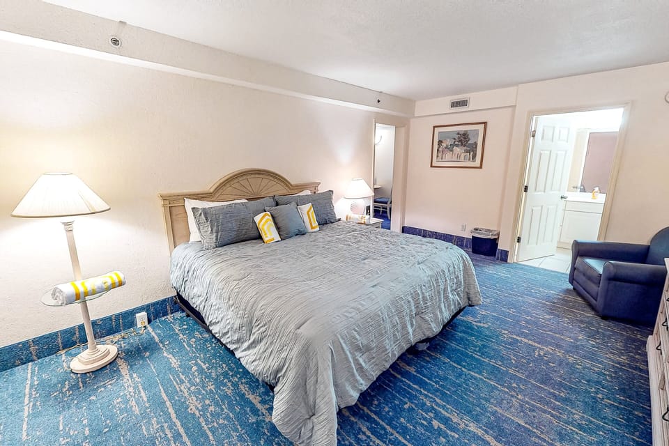 Relax in this bright king bedroom, perfect for your beach stay. Enjoy plenty of space, cozy seating, and direct access to the bathroom—an ideal retreat after a day on the sand and surf.