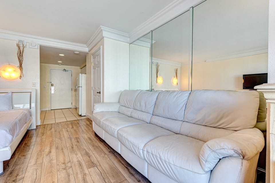 Enjoy this cozy beach stay studio featuring a plush sofa, warm lighting, and clean coastal décor—perfect for relaxing after a sunny day by the ocean.