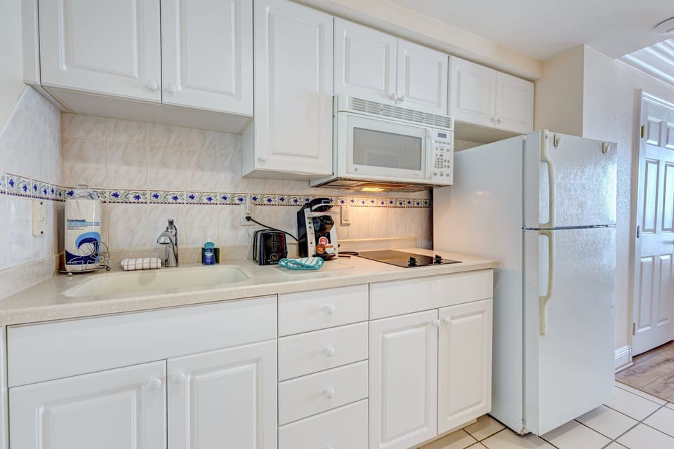 Enjoy convenient beach stay meals in this fully equipped kitchenette featuring a cooktop, microwave, fridge, toaster, and coffee maker—perfect for easy dining after a day by the ocean.