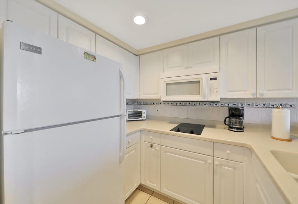 Clean, fully equipped beach-stay kitchenette featuring a fridge, stovetop, microwave, and coffee maker—perfect for preparing meals and adding comfort to your coastal getaway.