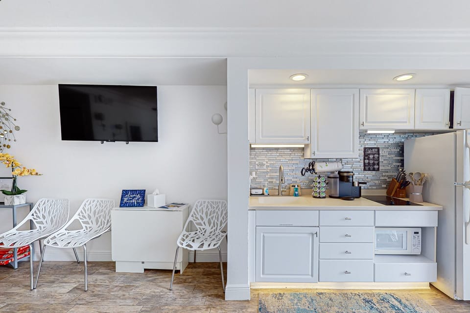 Bright, modern kitchenette with sleek appliances and comfy seating—perfect for unwinding after a sun-soaked beach stay. Enjoy coastal style, convenient amenities, and easy access to oceanfront fun.