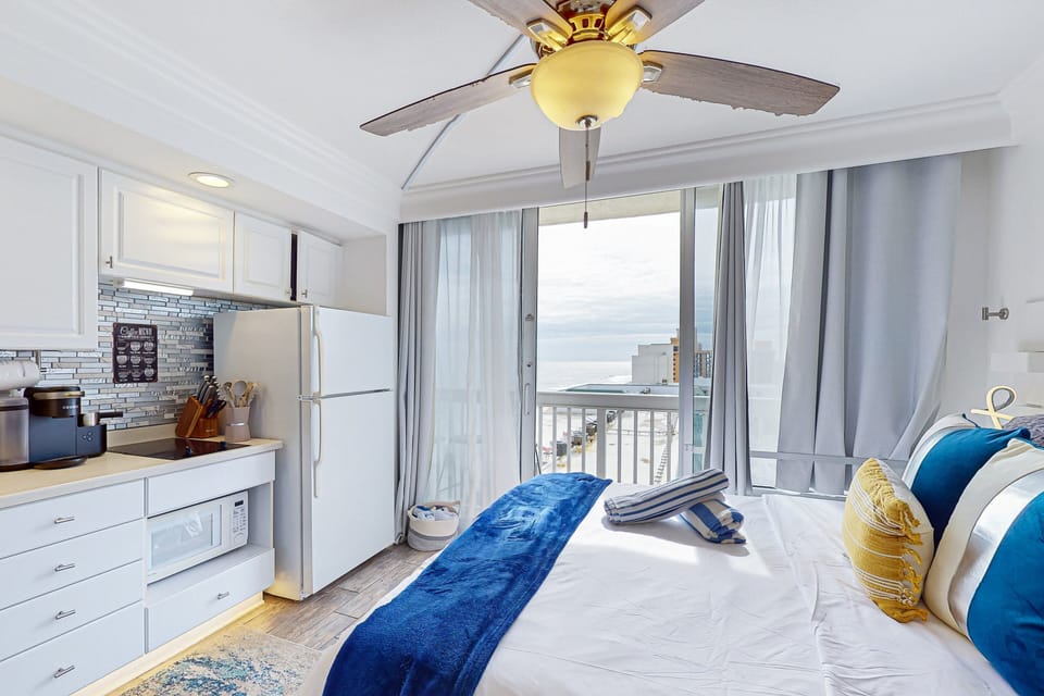 Charming beach stay studio featuring a crisp white kitchenette and cozy bed with ocean views. Enjoy relaxing coastal décor, modern amenities, and a bright, airy space just steps from the shoreline.