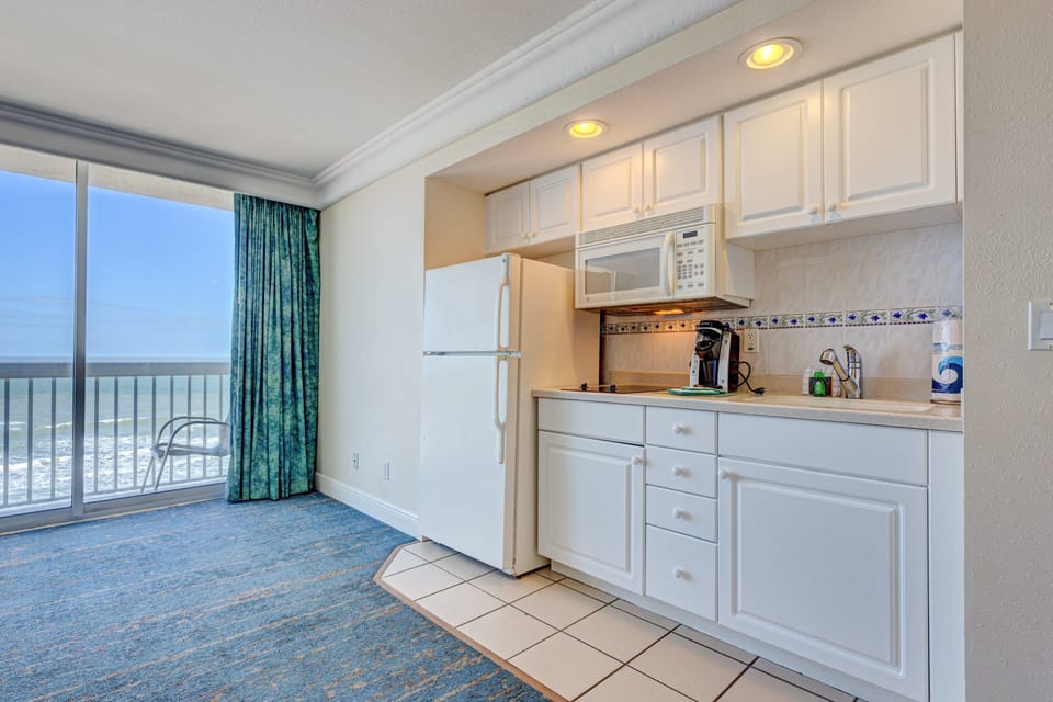 Bright oceanfront kitchenette featuring full appliances and sweeping beach views. Enjoy convenient in-room cooking and a relaxing coastal stay just steps from the shore.