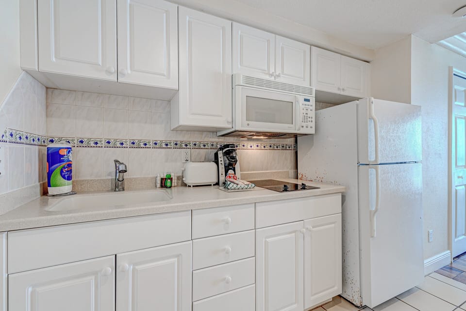 Cozy beachside kitchenette with full fridge, microwave, cooktop, and essentials—perfect for easy meal prep during your coastal stay. Clean, bright, and ready for your ocean getaway.