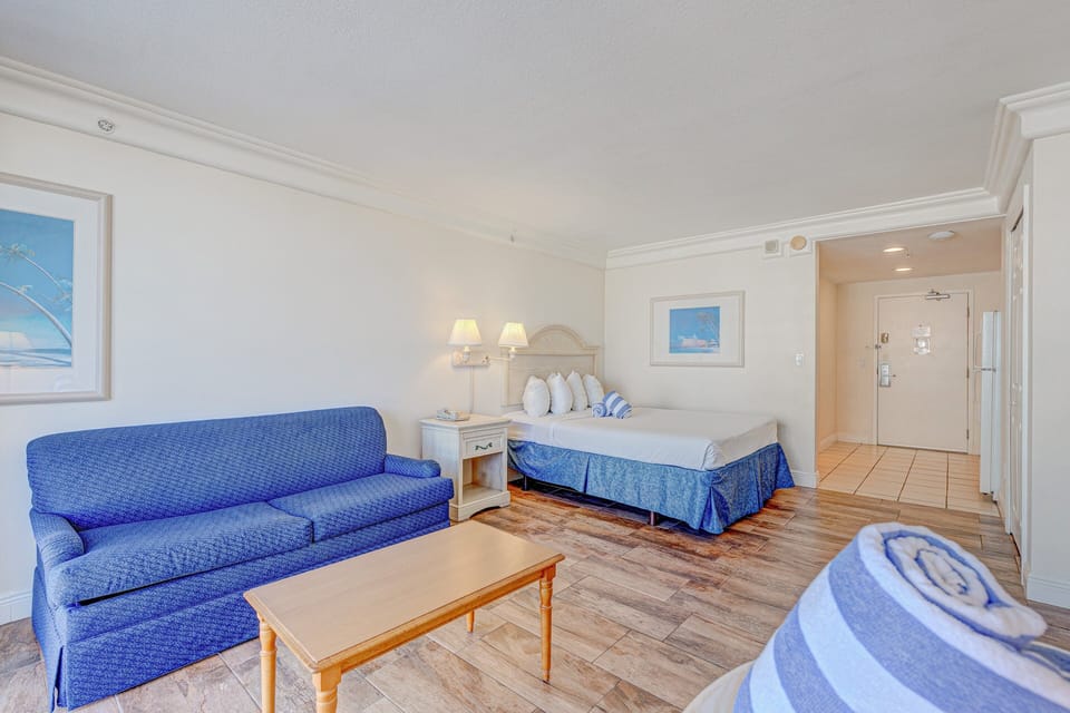 Inviting beach-style studio featuring a comfy bed, cozy sofa, and warm coastal décor. Enjoy a relaxed beach stay with open living space and soothing tones perfect for unwinding after sunny days by the shore.