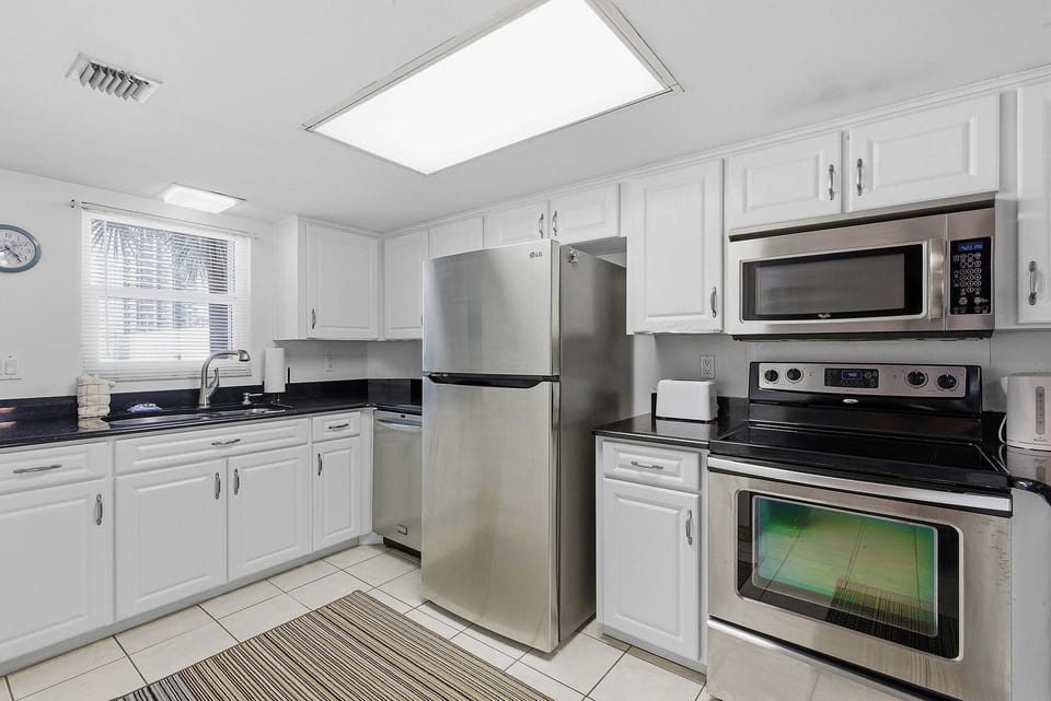 Prepare meals with ease during your beach stay in this bright, fully equipped kitchen featuring stainless steel appliances, ample counter space, and everything you need for a comfortable and convenient coastal getaway.