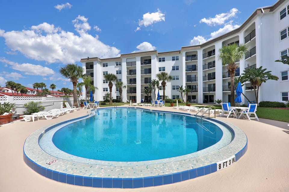 Enjoy this sparkling resort-style pool during your beach stay, complete with lounge chairs, palm trees, and sunny skies. The perfect place to relax, cool off, and soak up the coastal vibe just minutes from the beach.