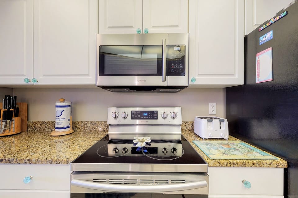 Prepare meals with ease in this clean, fully equipped kitchen featuring modern appliances and coastal touches—perfect for convenient dining during your relaxing beach stay.