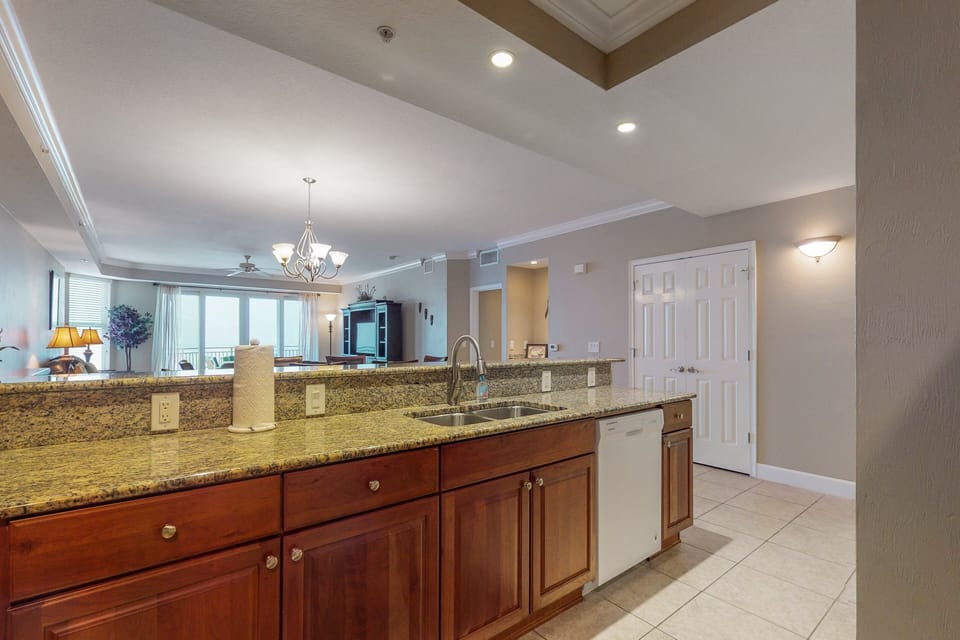 This bright kitchen offers granite countertops, modern appliances, and a large breakfast bar overlooking the living space. Ideal for easy meals, entertaining, and enjoying relaxed moments during your beach stay.