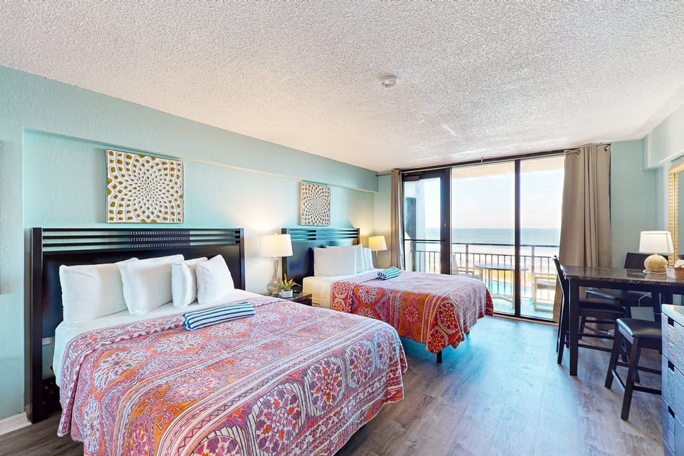 Relax during your beach stay in this bright oceanview bedroom featuring two comfortable beds, coastal décor, and sliding doors to a private balcony—perfect for soaking in sea breezes and enjoying a memorable beachfront vacation.