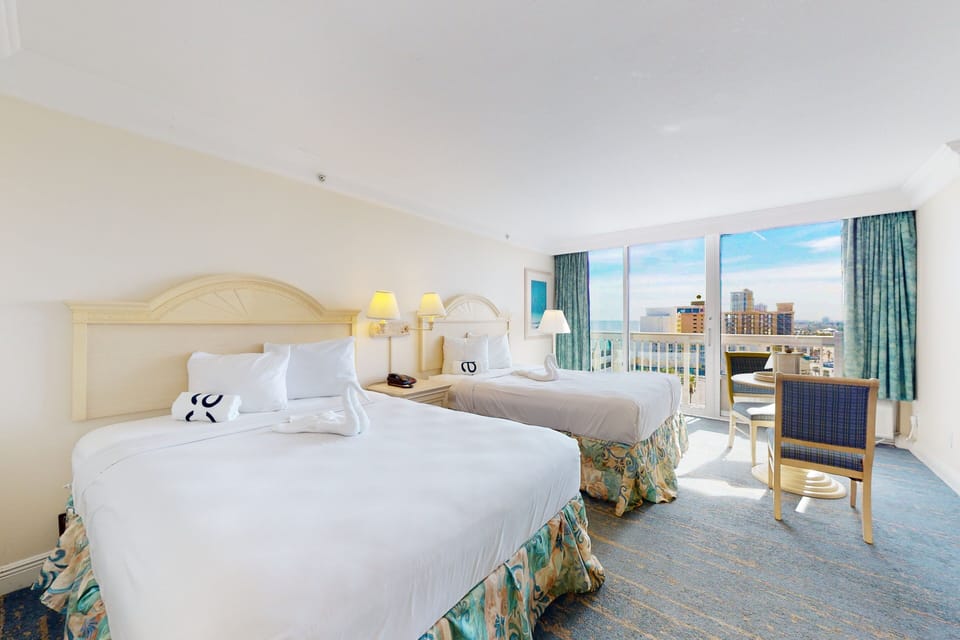 Inviting double room with two plush beds, vibrant décor, and a private balcony overlooking the shoreline—perfect for a relaxing beach stay with stunning coastal views.