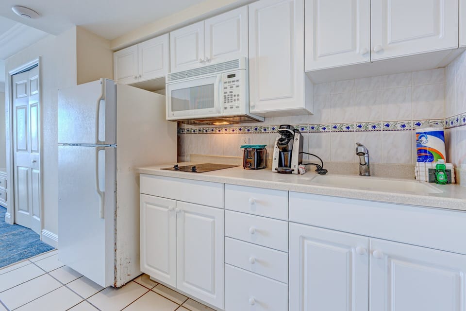 Convenient beach-stay kitchenette with stovetop, microwave, fridge, and coffee maker—perfect for quick meals and added comfort during your coastal getaway.